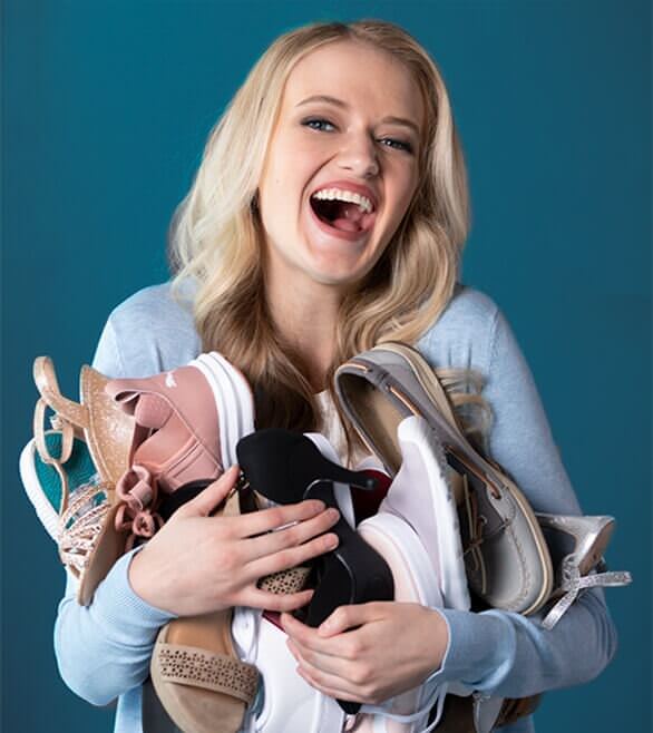 A happy woman with her arms full of shoes